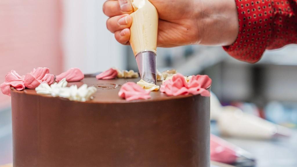 Hand-piping buttercream decorations onto a chocolate cake at Abba Cakes