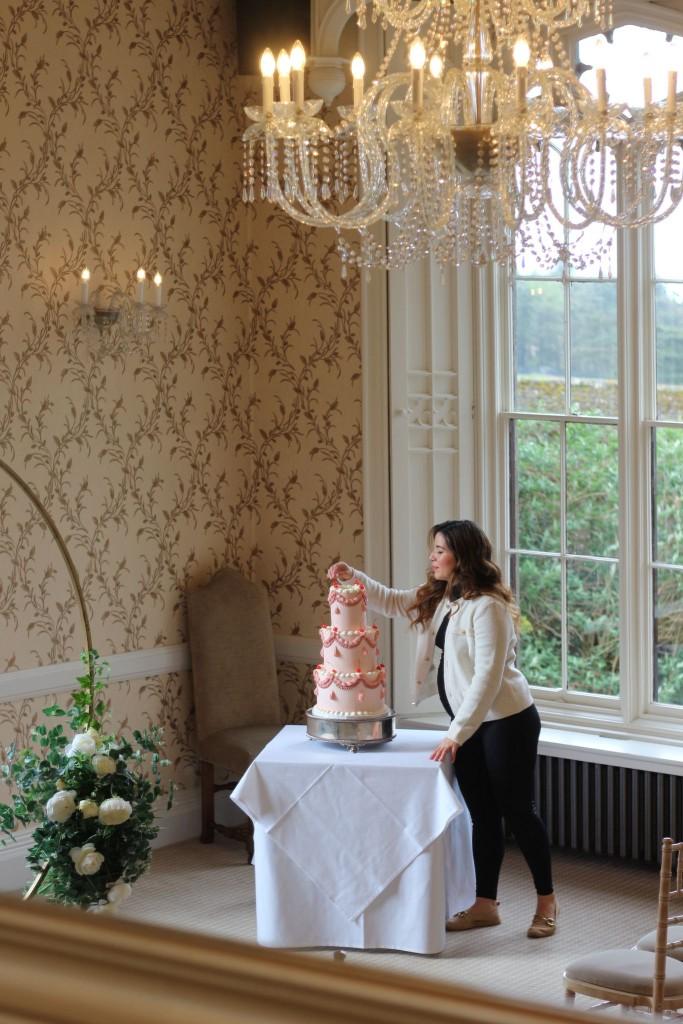Wedding cake being carefully finished in an elegant reception room