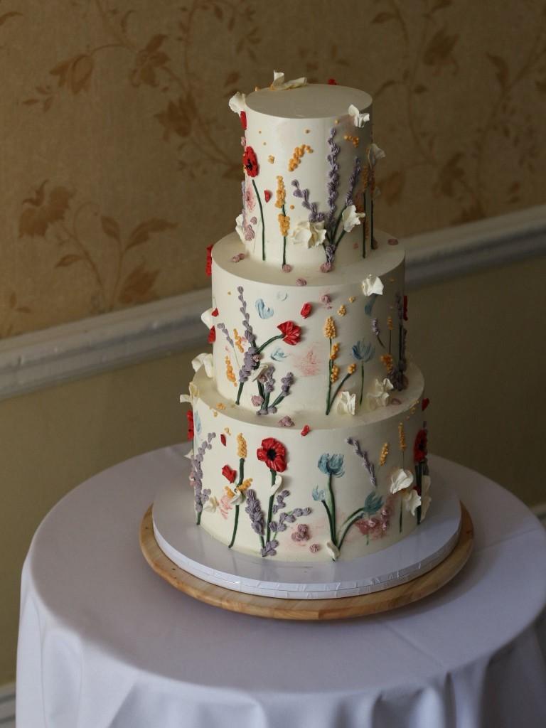 Romantic buttercream wedding cake with piped flowers and gold accents
