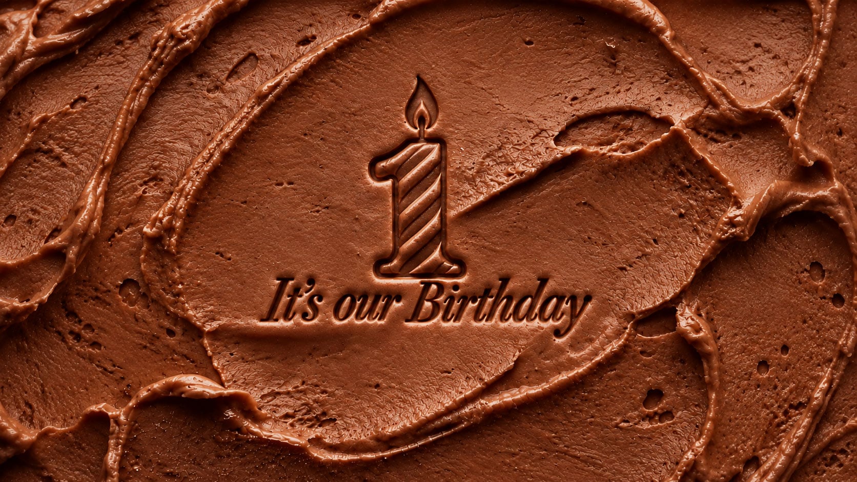 It’s our Birthday engraved into chocolate frosting with a number one candle